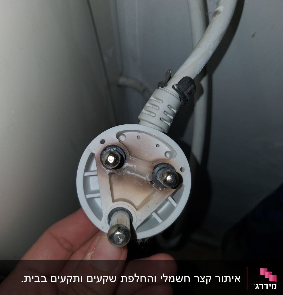 תקע חשמלי עם שלושה פינים ביד של אדם